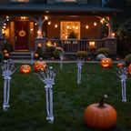 Skeleton arm stakes lining a front walkway at night