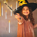 Girl in a witch hat waving the wand under floating candles